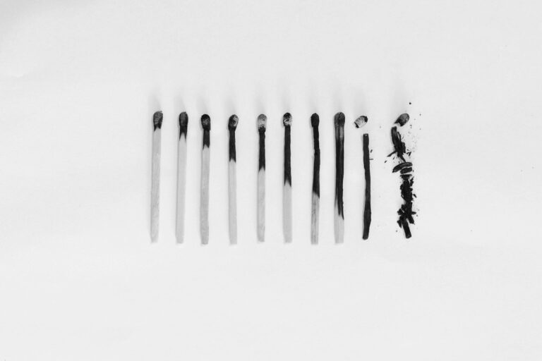 Artistic black and white image of burned matches arranged on a white background, symbolizing burnout.