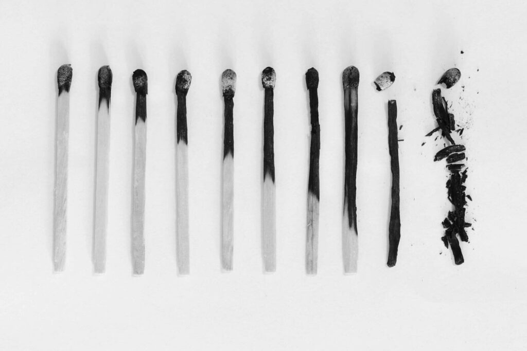 Artistic black and white image of burned matches arranged on a white background, symbolizing burnout.